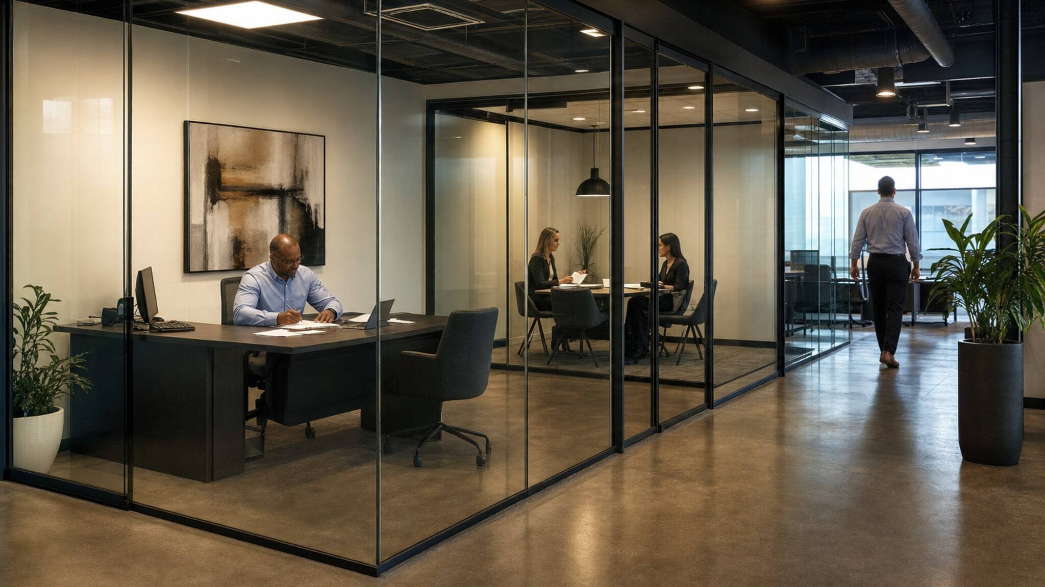 Frameless glass walls creating offices and meeting rooms in a modern workspace.